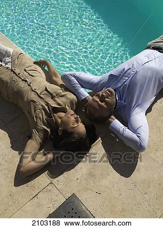 High angle view of couple lying on floor at poolside View Large Photo Image Stock Photo - High angle view of couple lying on floor at poolside . Fotosearch