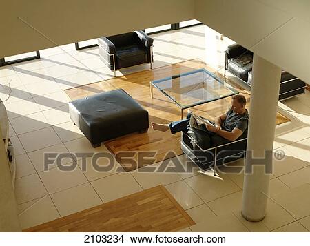 Picture - High angle view of man reading newspaper in armchair . Fotosearch