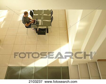 High angle view of man working on laptop at table View Large Photo Image Stock Photo - High angle view of man working on laptop at table . Fotosearch
