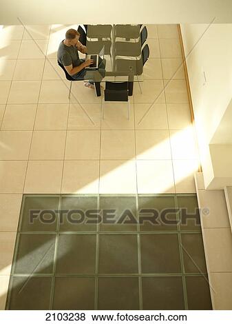 Stock Photo - High angle view of man working on laptop at table . Fotosearch