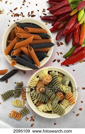 Stock Photo - High angle view of two bowls of raw pasta and red chili peppers . Fotosearch
