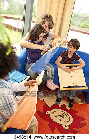 Kindergarten teacher and children playing with fasteners frames, elevated view View Large Photo Image Picture - Kindergarten teacher and children playing with fasteners frames, elevated view . Fotosearch
