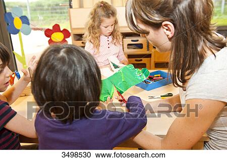 Kindergarten teacher doing handicrafts with children View Large Photo Image Stock Image - Kindergarten teacher doing handicrafts with children . Fotosearch