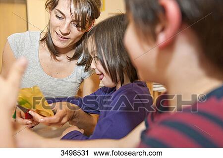 Stock Image - Kindergarten teacher doing handicrafts with children, low angle view . Fotosearch