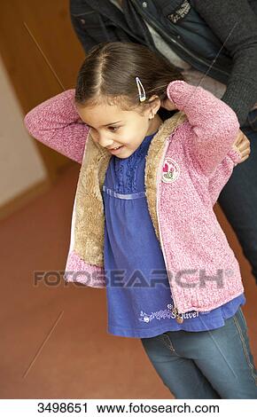 Kindergarten teacher helping young girl to put on her jacket View Large Photo Image Stock Image - Kindergarten teacher helping young girl to put on her jacket . Fotosearch