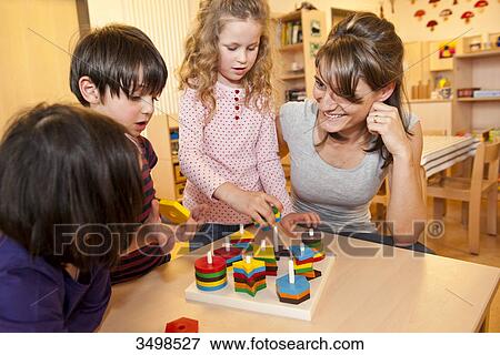 Stock Photo - Kindergarten teacher playing with children . Fotosearch