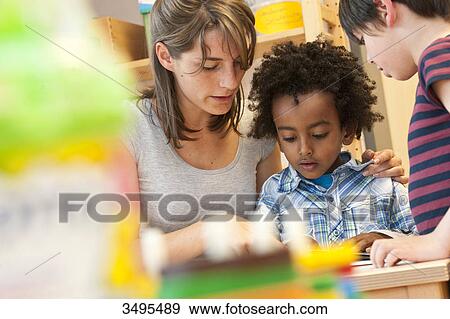 Kindergarten teacher reading with children, low angle view View Large Photo Image Stock Photo - Kindergarten teacher reading with children, low angle view . Fotosearch