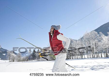 Stock Photography - Laughing woman with skis in winter landscape, Tannheimer Tal, Tyrol, Austria . Fotosearch