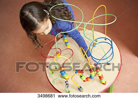 Stock Image - Little girl playing with an educational toy, elevated view . Fotosearch