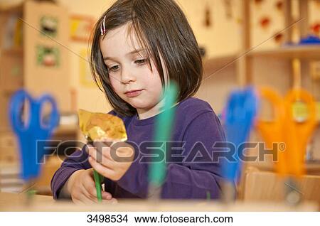 Little girl using scissors to cut paper, low angle view View Large Photo Image Picture - Little girl using scissors to cut paper, low angle view . Fotosearch