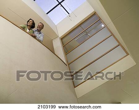 Stock Photo - Low angle view of couple leaning against wall and smiling . Fotosearch