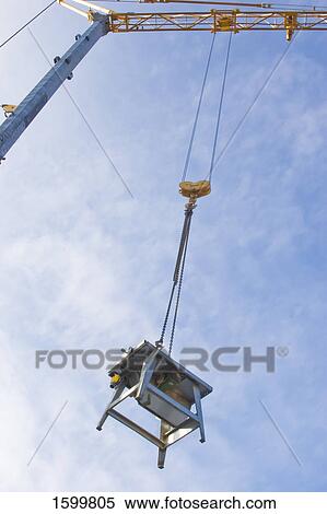 Stock Photography - Low angle view of crane lifting table . Fotosearch