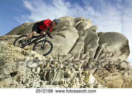 Low angle view of man cycling at coast, Capo Testa, Italy View Large Photo Image Stock Photo - Low angle view of man cycling at coast, Capo Testa, Italy . Fotosearch