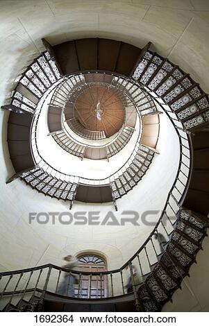 Low angle view of people walking down spiral staircase View Large Photo Image Picture - Low angle view of people walking down spiral staircase . Fotosearch