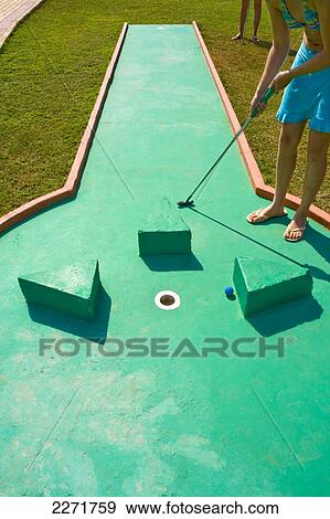 Stock Photo - Low section view of woman playing miniature golf . Fotosearch