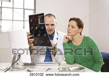 Stock Image - Male doctor showing x-ray report to patient . Fotosearch