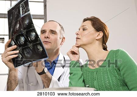 Stock Image - Male doctor showing x-ray report to patient . Fotosearch