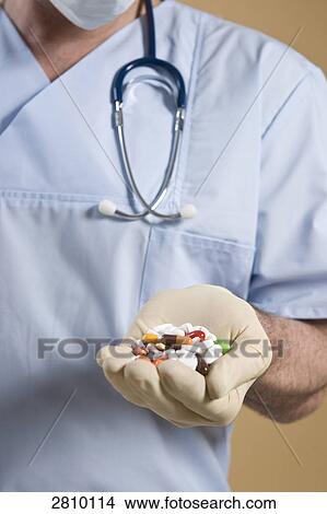 Picture - Male surgeon holding pills . Fotosearch