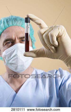 Stock Image - Male surgeon holding vial . Fotosearch