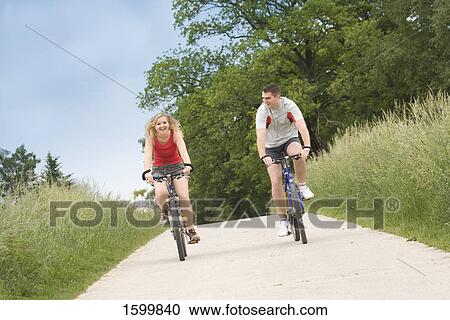 Man and woman cycling on road View Large Photo Image Stock Image - Man and woman cycling on road . Fotosearch
