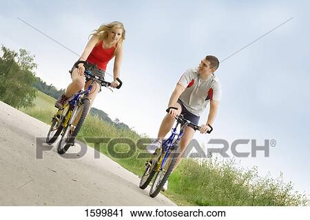 Stock Image - Man and woman cycling on road . Fotosearch