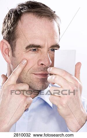 Man holding hand mirror and examining his face View Large Photo Image Stock Image - Man holding hand mirror and examining his face . Fotosearch
