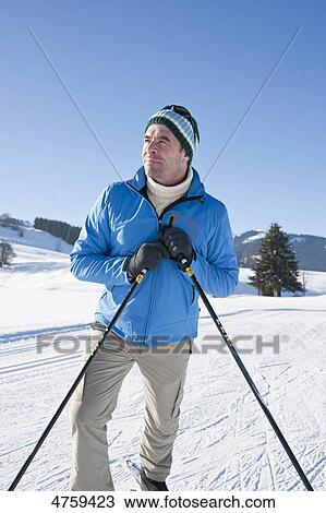 Stock Image - Man in winter landscape looking around, Tannheimer Tal, Tyrol, Austria . Fotosearch