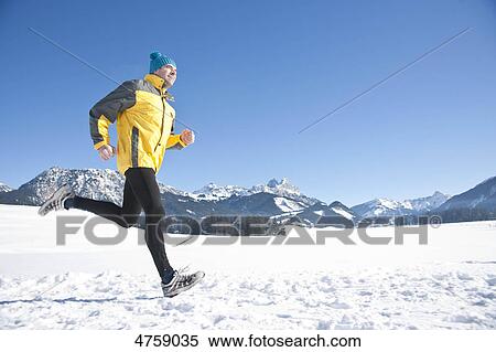 Stock Photography - Man jogging in snow, Tannheimer Tal, Tyrol, Austria . Fotosearch