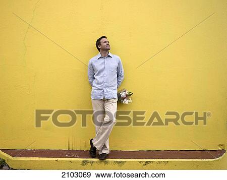 Man leaning against wall and holding bouquet of flowers View Large Photo Image Stock Photo - Man leaning against wall and holding bouquet of flowers . Fotosearch