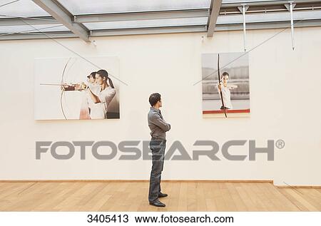 Man looking at photos on wall View Large Photo Image Stock Image - Man looking at photos on wall . Fotosearch