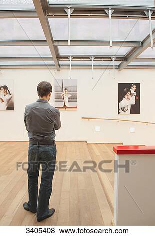 Man looking at photos on wall View Large Photo Image Stock Photo - Man looking at photos on wall . Fotosearch