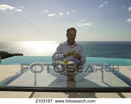 Stock Photo - Man peeling apple at poolside . Fotosearch