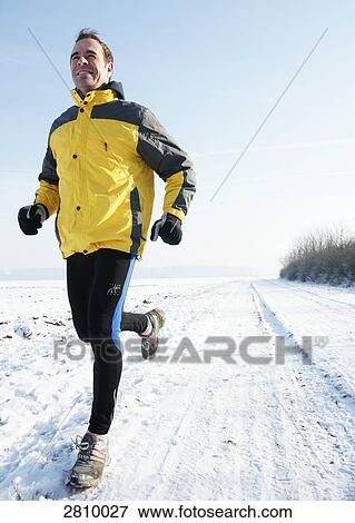 Man running in snow covered landscape View Large Photo Image Stock Photo - Man running in snow covered landscape . Fotosearch