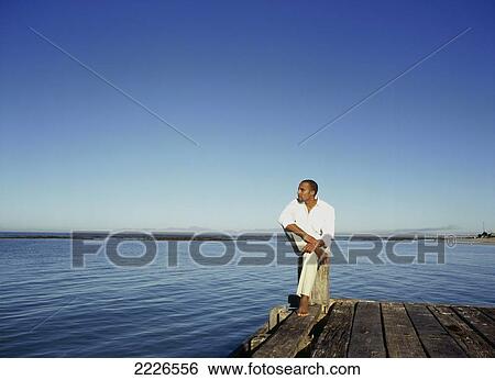 Man sitting on pier View Large Photo Image Stock Photograph - Man sitting on pier . Fotosearch