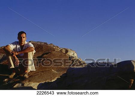 Man sitting on rock View Large Photo Image Stock Image - Man sitting on rock . Fotosearch