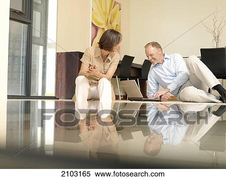 Man using laptop with his wife sitting beside him View Large Photo Image Stock Photography - Man using laptop with his wife sitting beside him . Fotosearch