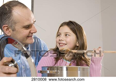 Stock Photo - Man with his daughter smelling food in kitchen . Fotosearch