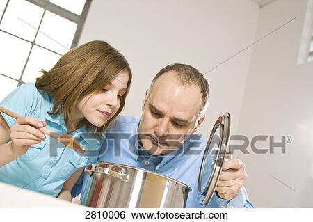 Stock Photograph - Man with his daughter smelling food in kitchen . Fotosearch