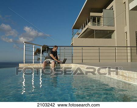 Man working on laptop at poolside View Large Photo Image Stock Image - Man working on laptop at poolside . Fotosearch