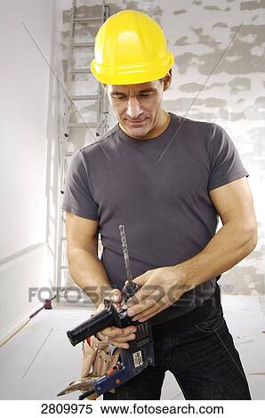 Stock Photography - Manual worker holding hand drill . Fotosearch