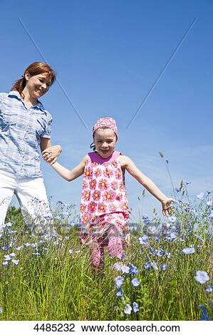 Mother and daughter running over flower meadow View Large Photo Image Stock Image - Mother and daughter running over flower meadow . Fotosearch