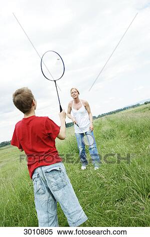 Stock Photography - Mother and son playing badminton on a meadow . Fotosearch