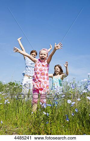 Mother and two daughters running over flower meadow View Large Photo Image Stock Image - Mother and two daughters running over flower meadow . Fotosearch