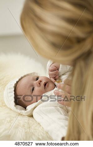 Stock Photo - Mother looking at lying baby . Fotosearch