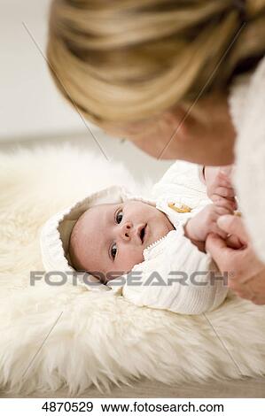 Stock Photo - Mother looking at lying baby . Fotosearch