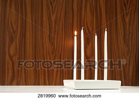 Stock Image - One candle burning out of four . Fotosearch