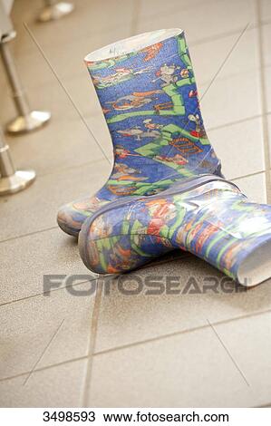 Stock Image - Pair of rubber boots on a tiled floor . Fotosearch