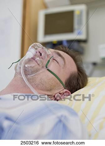 Stock Photograph - Patient wearing oxygen mask in hospital . Fotosearch