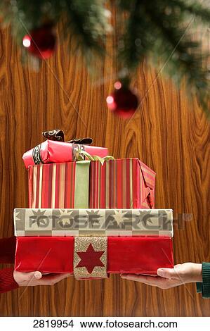Picture - People's hands holding Christmas present . Fotosearch