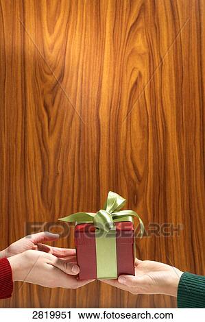 Stock Image - People's hands holding Christmas present . Fotosearch